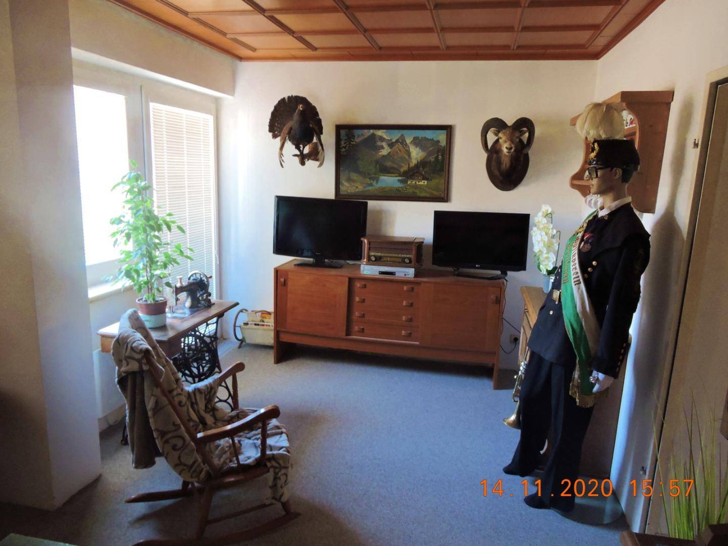 Wohnzimmer mit zwei Fernsehern, Holzschrank und traditioneller Jagdtrophäen-Dekoration.