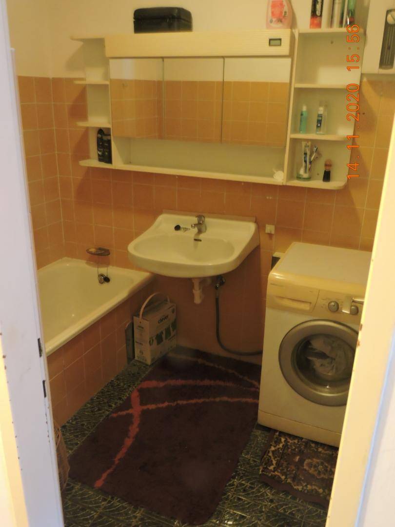 Badezimmer mit orangefarbenen Fliesen, Badewanne und Waschbecken.