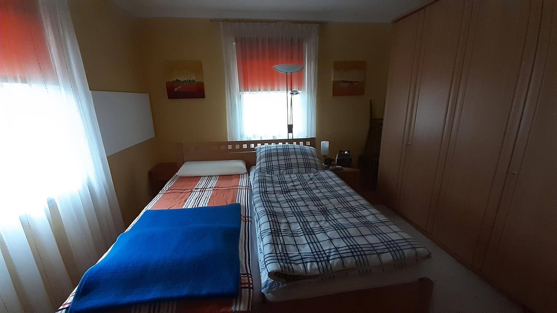 Gemütliches Schlafzimmer mit zwei Einzelbetten, Holzmöbeln und einem Fenster für natürliches Licht.