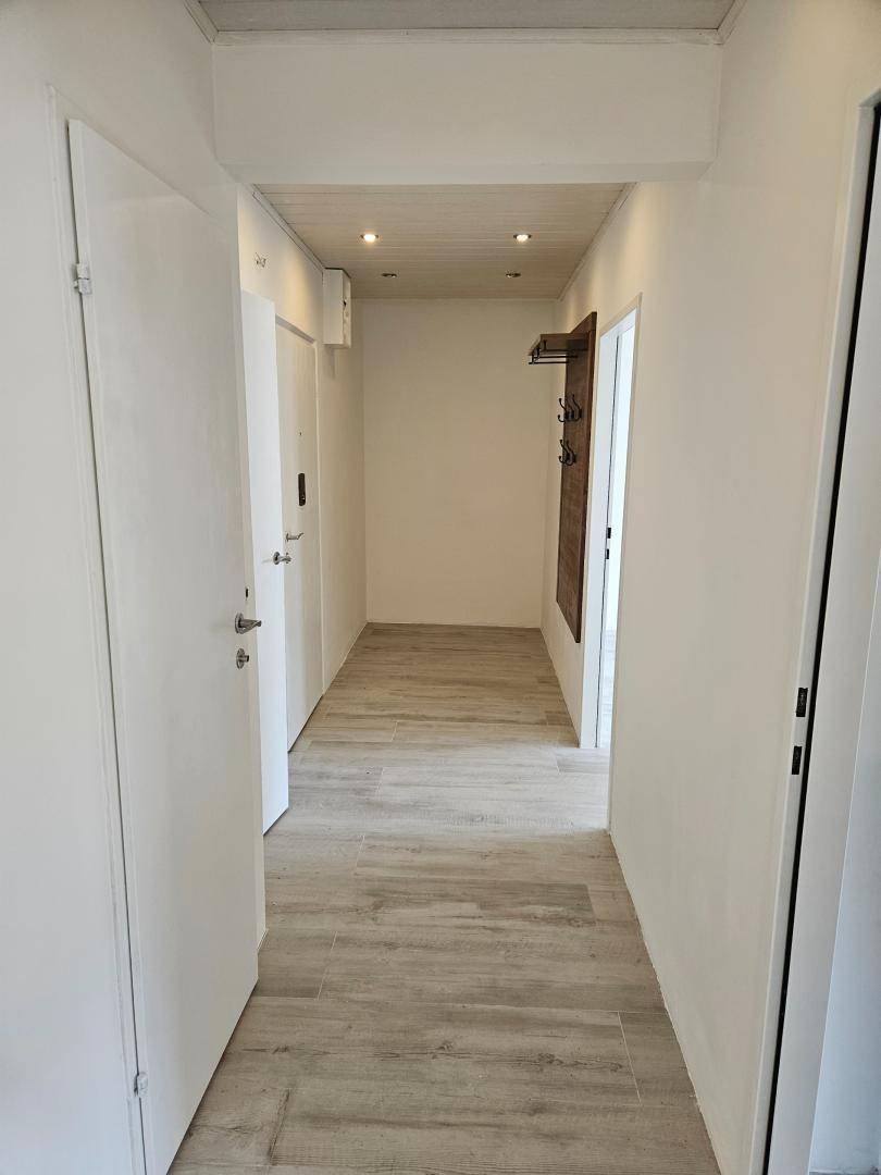 Heller Flur mit modernem Fliesenboden in Holzoptik und einer Decke mit Holzakzenten.