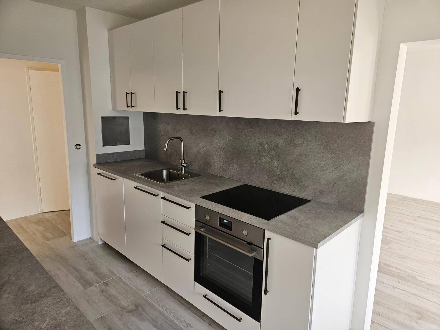Funktionale Küchenzeile mit Spüle, Induktionskochfeld und Backofen in modernem, hellem Design.