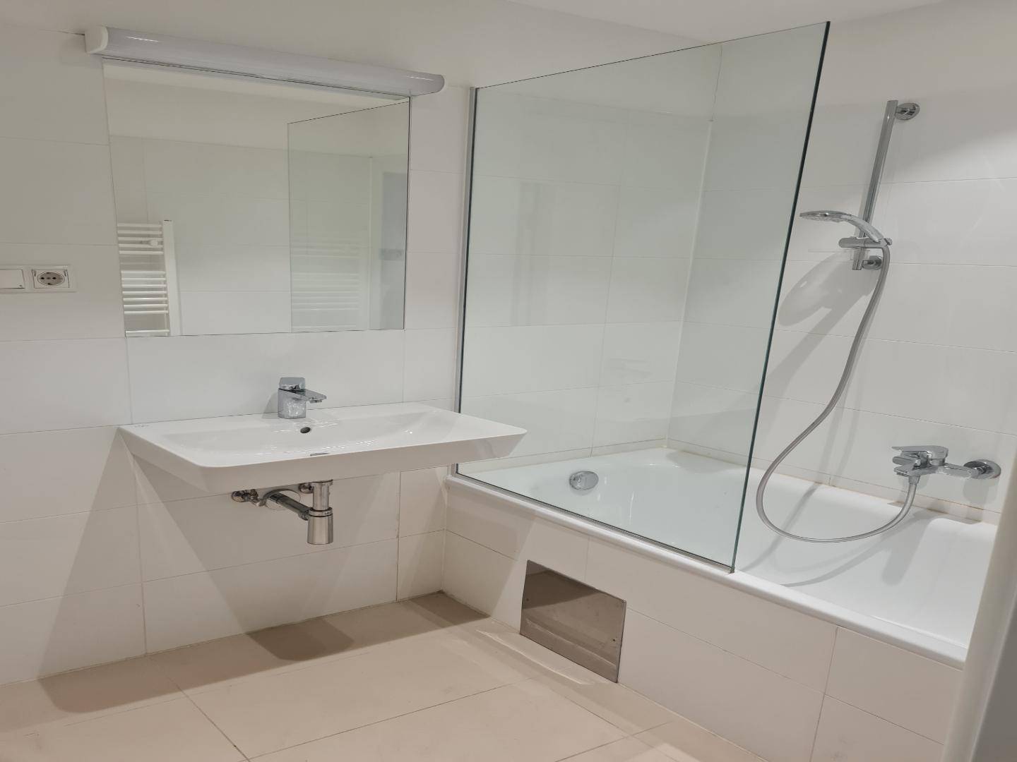 Helles Badezimmer mit Badewanne, Duschabtrennung aus Glas und modernem Waschbecken.