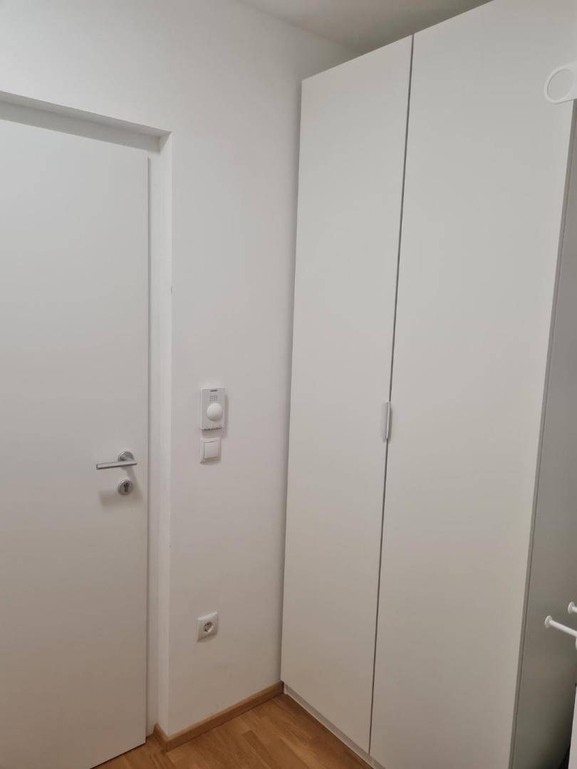 Weißer Kleiderschrank neben einer Tür in einem hellen Raum.