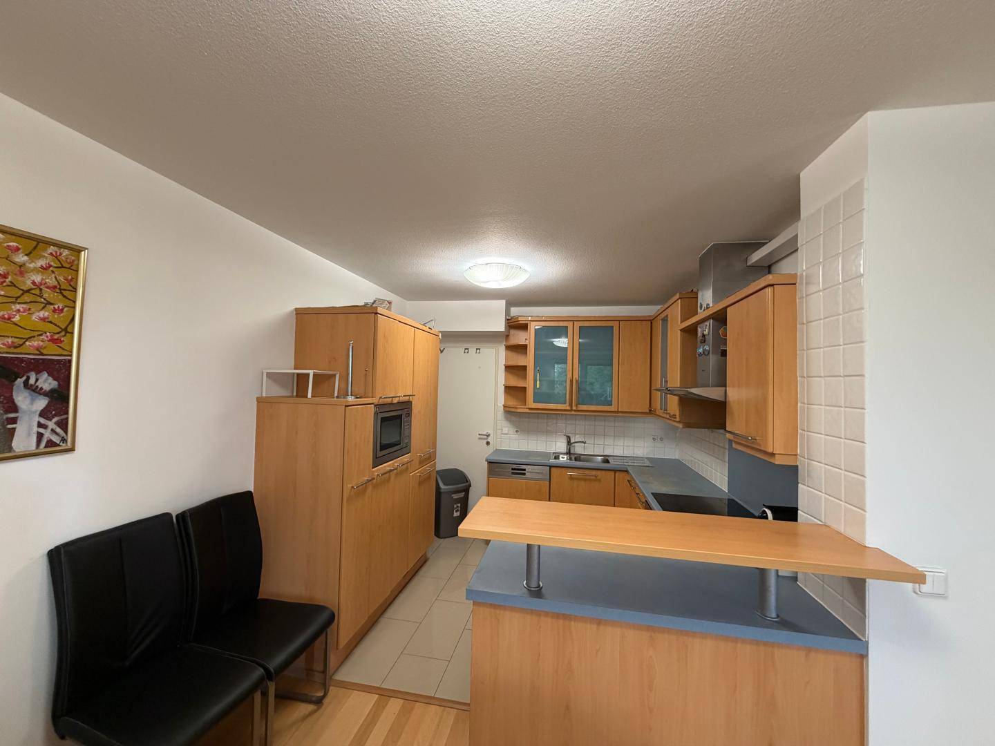 Funktionale Küche mit Holzschränken, integrierter Mikrowelle und einer kleinen Frühstücksbar.