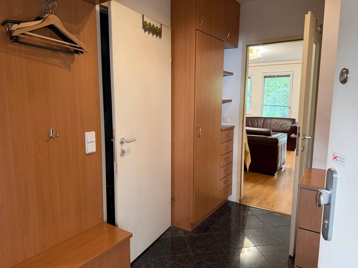 Heller Flur mit Einbauschränken und Blick in das angrenzende Wohnzimmer.
