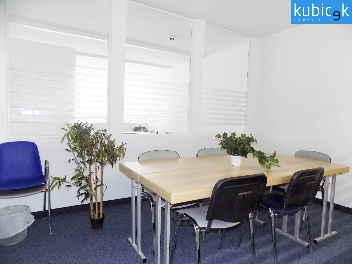 Funktionaler Besprechungsraum mit großem Tisch, bequemen Stühlen und viel Tageslicht durch Fenster.