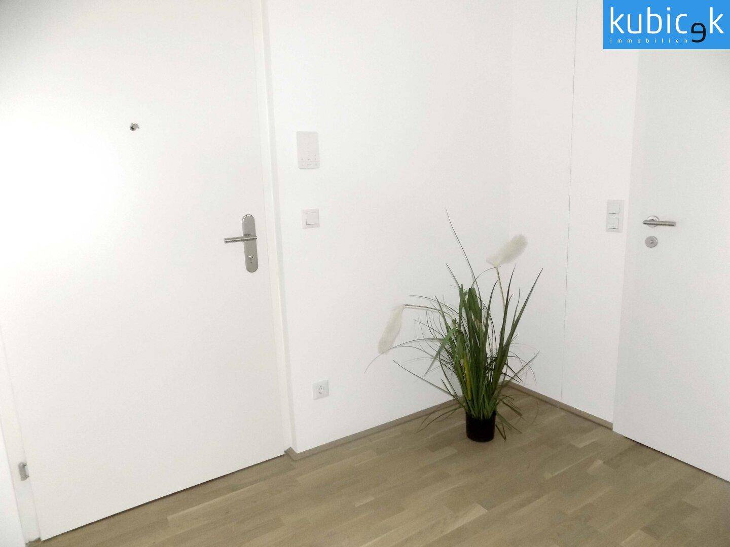 Eingangsbereich der Wohnung mit Parkettboden und weißen Türen, hell und einladend.