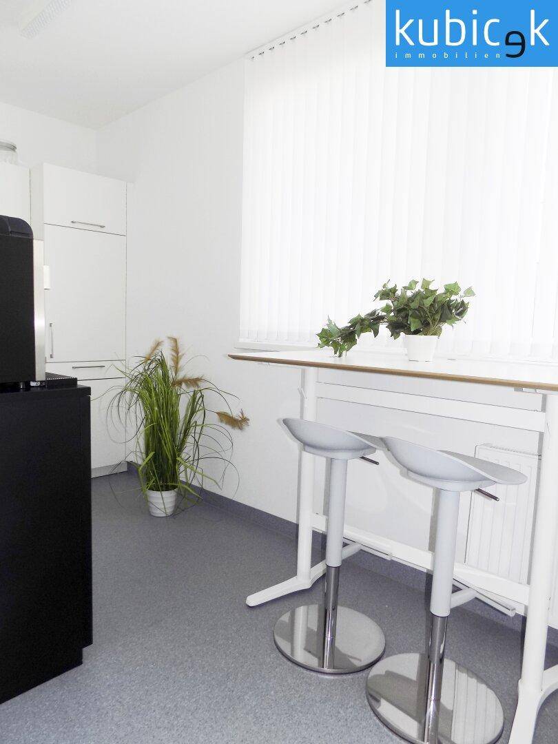 Küchenzeile mit einem Stehtisch und zwei Barhockern, ideal für kurze Pausen oder informelle Treffen.