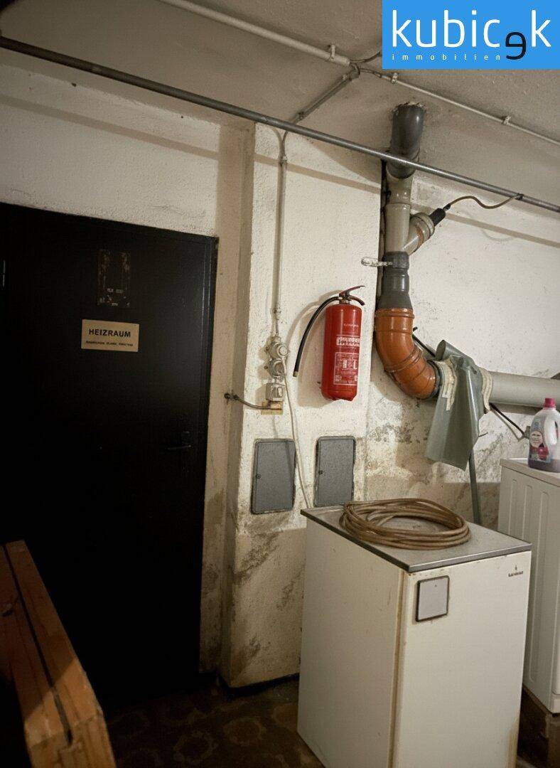 Heizraum im Keller mit technischen Installationen und Feuerlöscher.