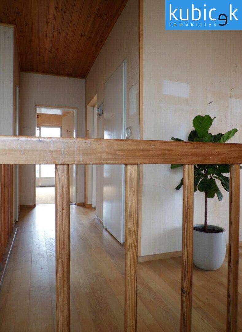 Flur im Obergeschoss mit Holzgeländer und Blick in weitere Räume.