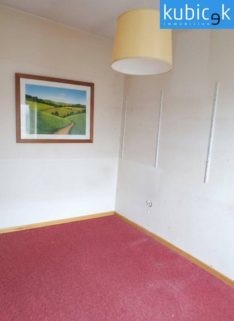Schlafzimmer mit rotem Teppichboden und einem Bild an der Wand.