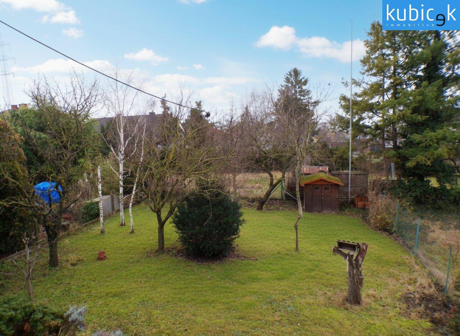 Großer Garten mit Rasenfläche, Bäumen und einem kleinen Gartenhaus.