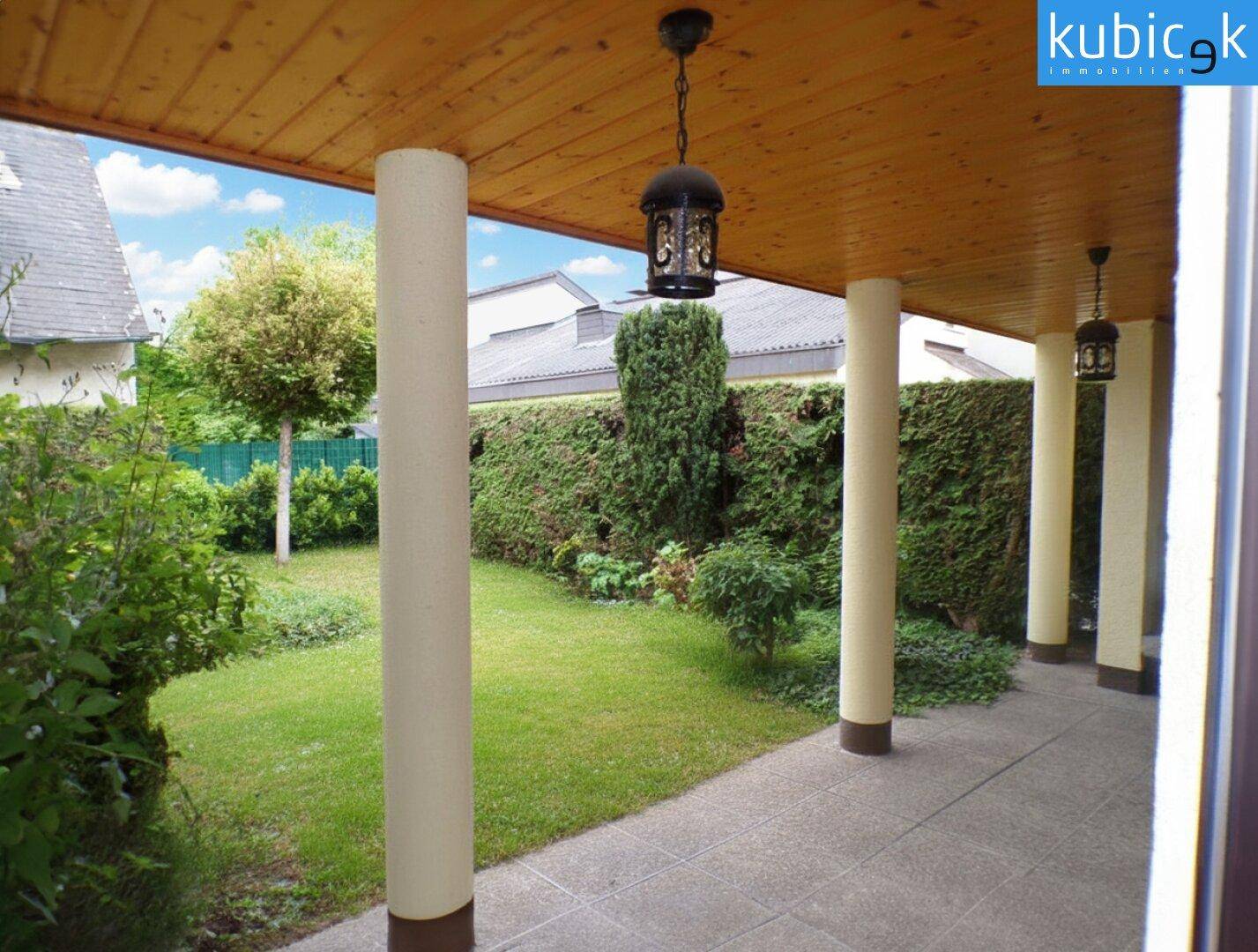 Überdachte Terrasse mit Holzdach und Blick auf den grünen Gartenbereich.