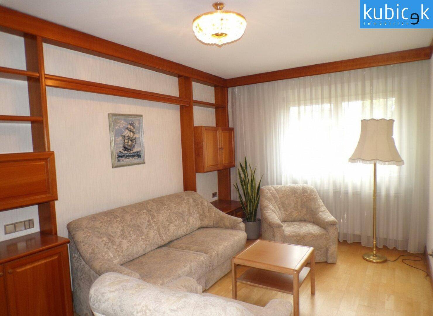 Wohnzimmer mit Holzregalen, beigen Sofas und hellem Parkettboden.