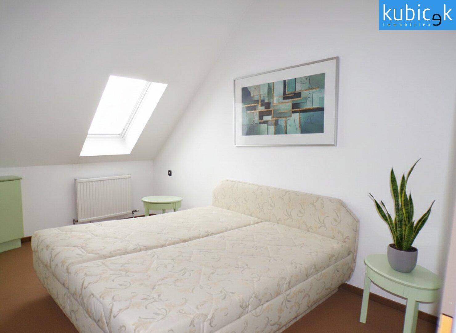 Helles Schlafzimmer im Dachgeschoss mit zwei Einzelbetten und Dachfenster.
