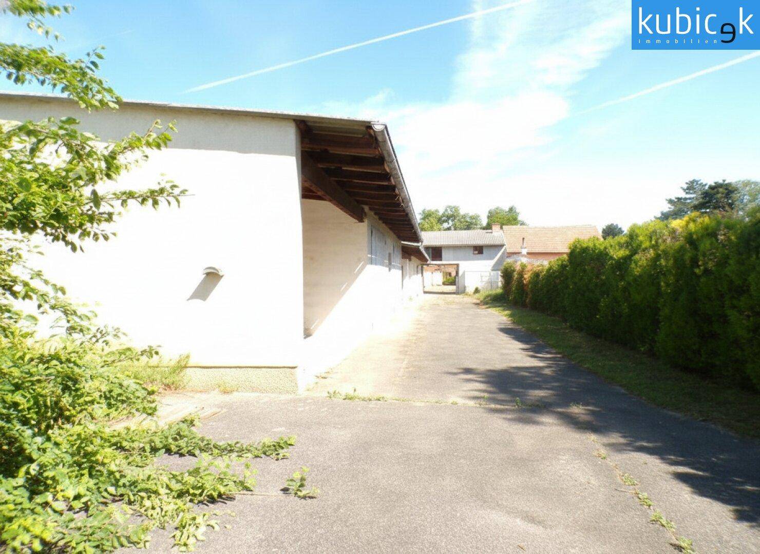Seitenansicht eines Gebäudes mit einer Zufahrt und gepflegten Hecken.