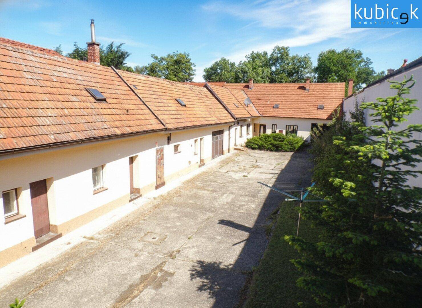 Weitläufiger Innenhof, umgeben von Gebäuden mit Ziegeldächern und Grünflächen.