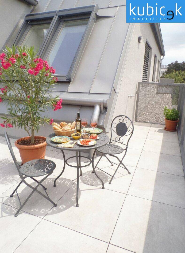 Gemütliche Dachterrasse mit Esstisch, Pflanzen und Blick auf die umliegenden Häuser.