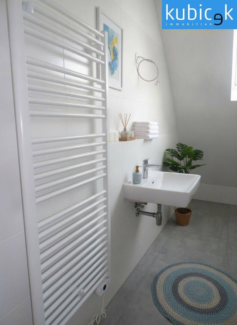 Modernes Badezimmer mit Waschbecken, beheiztem Handtuchhalter und schrägen Wänden.