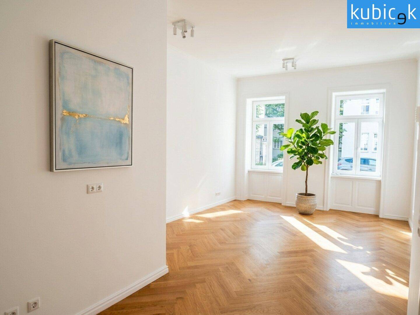 Geräumiges, helles Zimmer mit Fischgrätparkett und moderner Kunst an der Wand.
