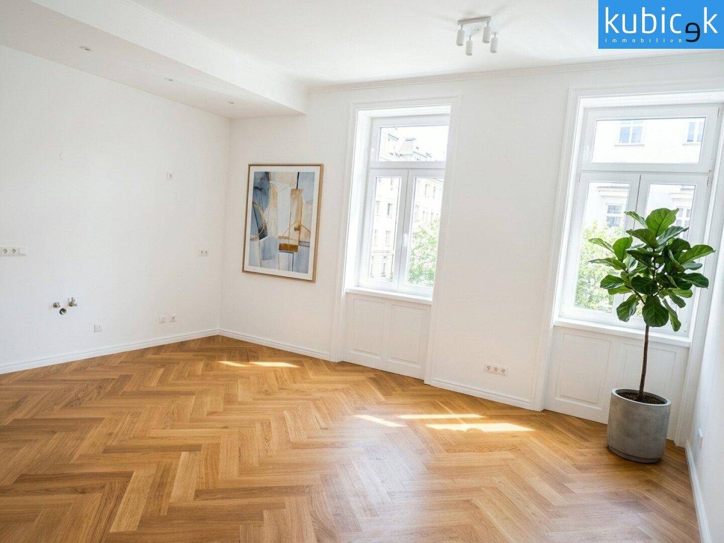 Geräumiges Zimmer mit Fischgrätparkett, großen Fenstern und viel Tageslicht.