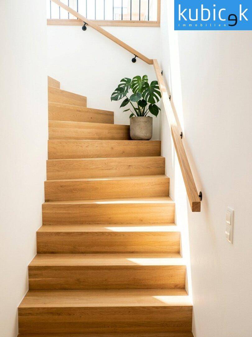 Moderne Holztreppe mit schlichtem Geländer und natürlichem Lichteinfall in einem hellen Flur.