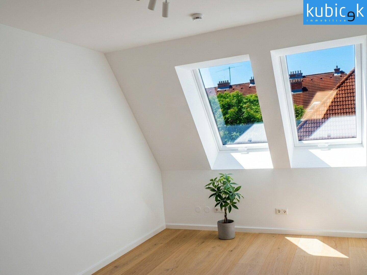 Dachgeschosszimmer mit Dachfenstern, Holzboden und schrägen Wänden, ideal für Schlaf- oder Arbeitszimmer.