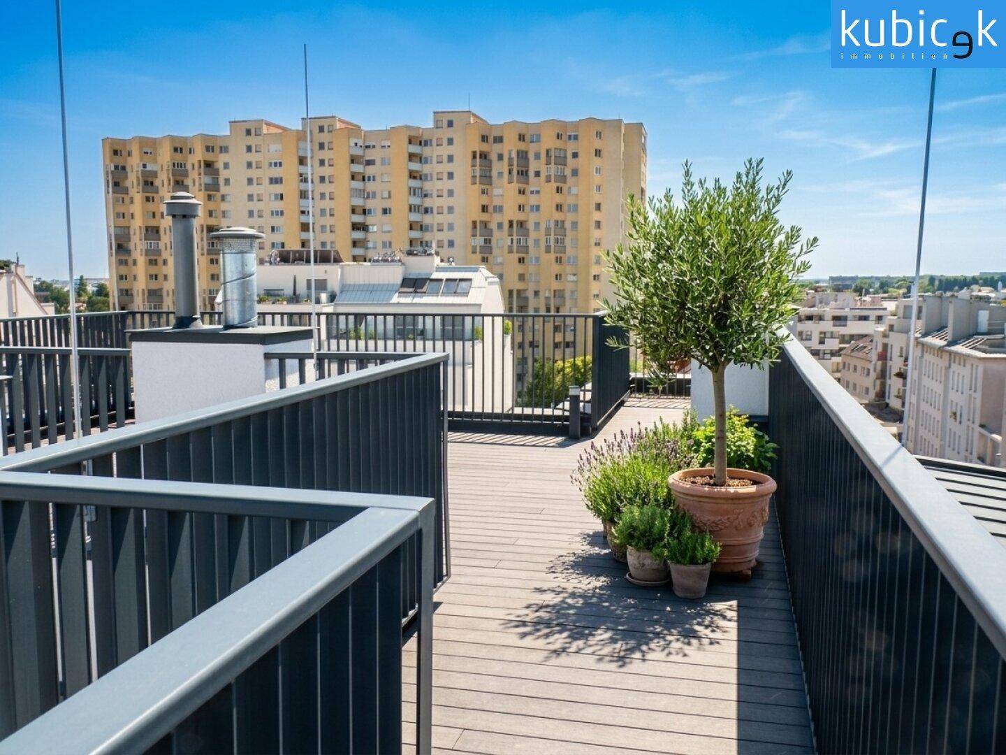 Dachterrasse mit Holzboden, robustem Metallgeländer und Blick auf umliegende Gebäude.