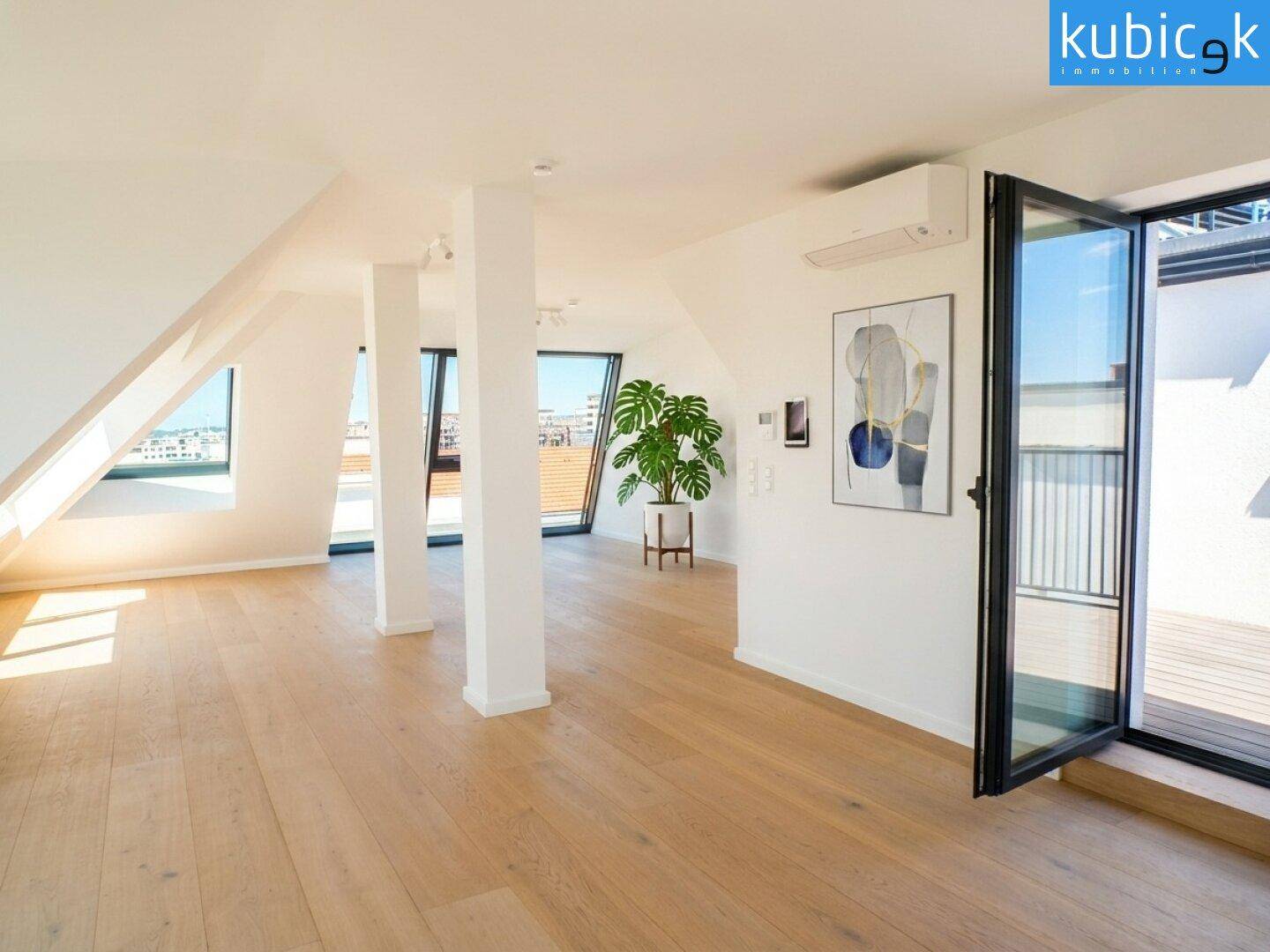 Geräumiger Dachgeschossbereich mit Holzboden, Klimaanlage und Zugang zu einer sonnigen Dachterrasse.