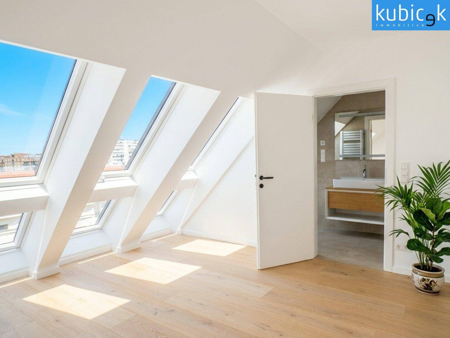 Helles Schlafzimmer im Dachgeschoss mit Holzboden, vielen Dachfenstern und direktem Zugang zum Badezimmer.