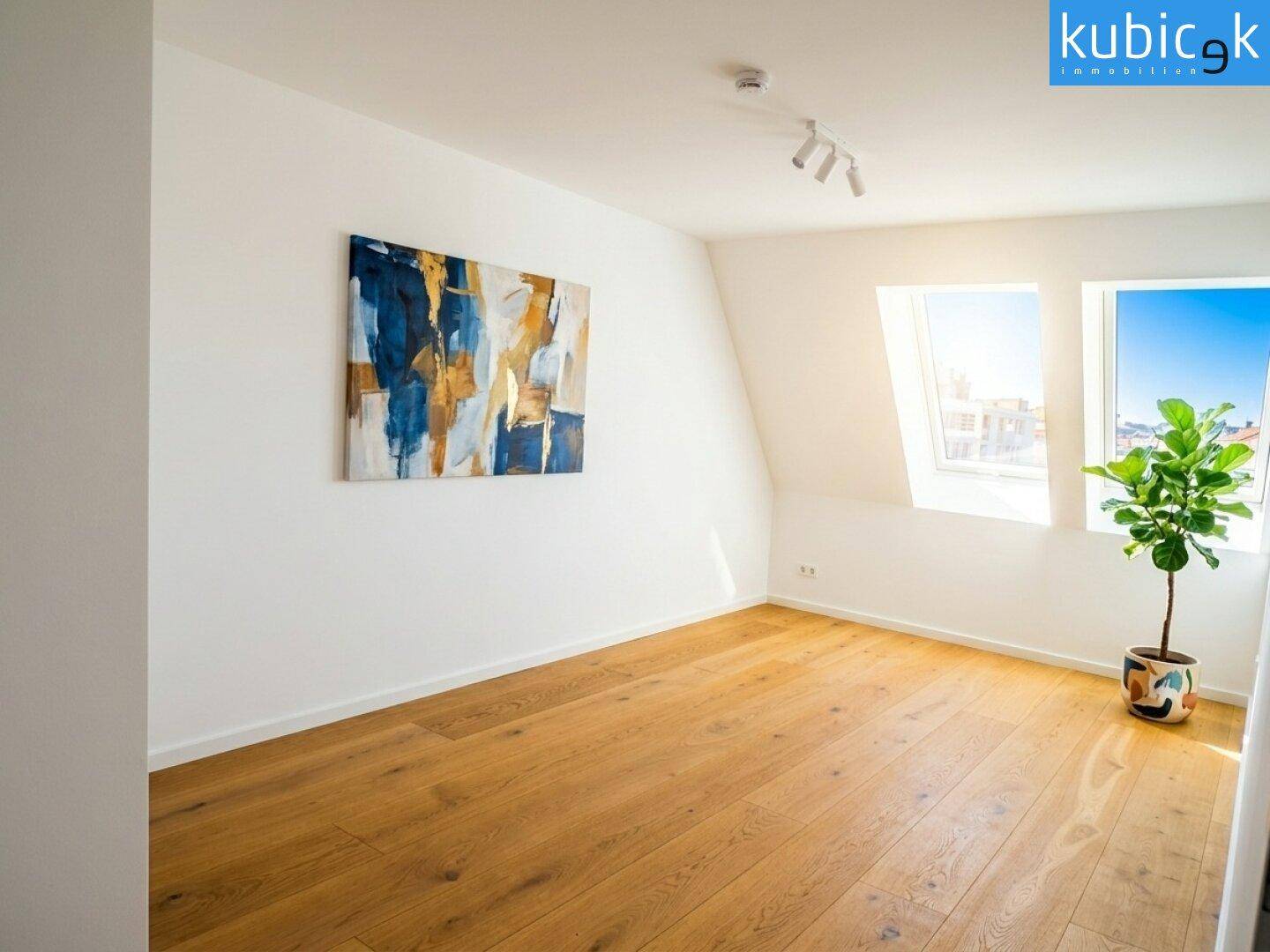 Geräumiges Schlafzimmer im Dachgeschoss mit Holzboden, Kunstwerk und Blick durch die Dachfenster.