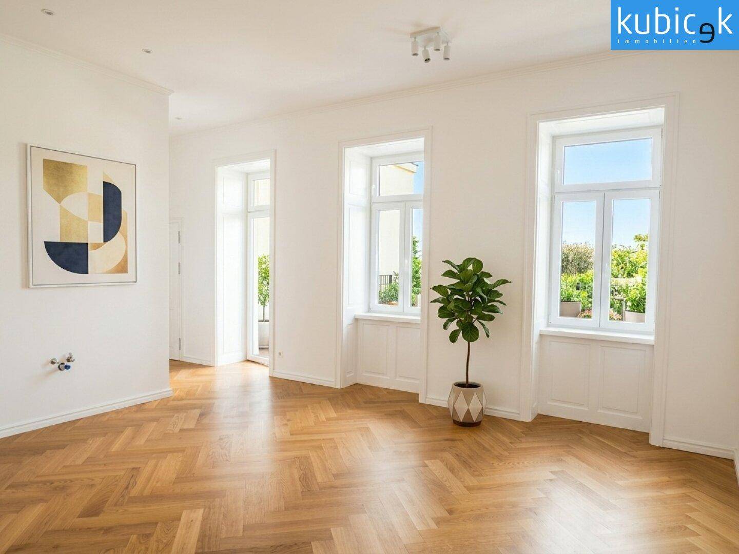 Geräumiges Wohnzimmer mit Fischgrätparkett, hohen Fenstern und Zugang zu einem Balkon.