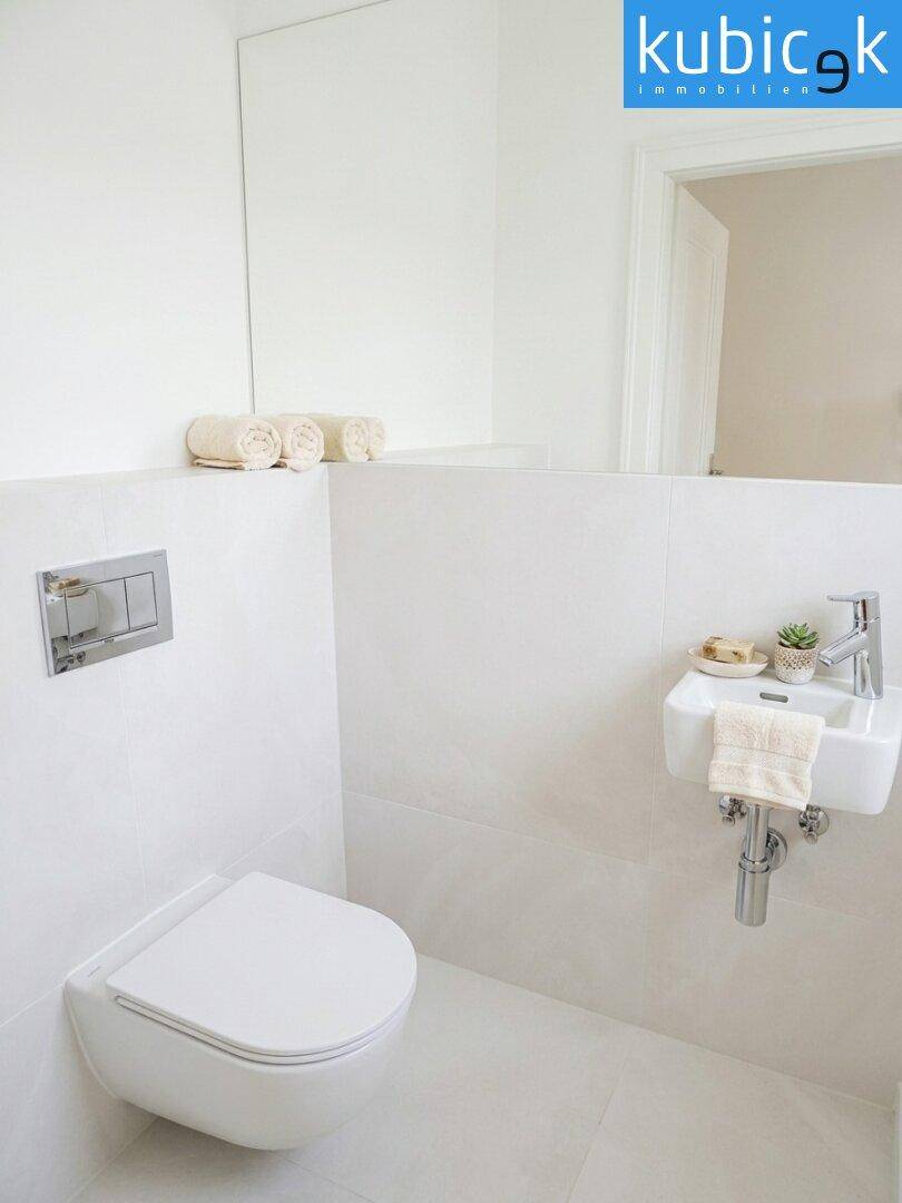 Modernes Gäste-WC mit wandhängender Toilette und kleinem Waschbecken, minimalistisch gestaltet.