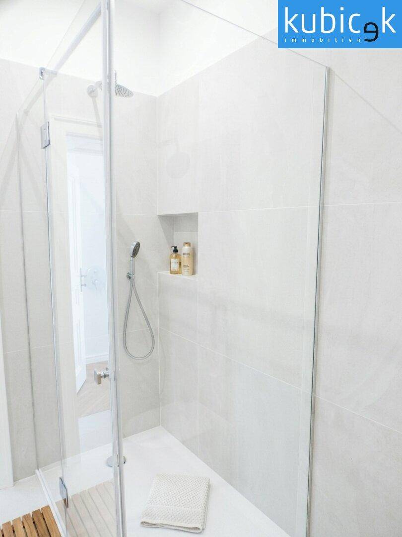 Geräumige, begehbare Dusche mit Glasabtrennung und integrierter Nische im modernen Badezimmer.