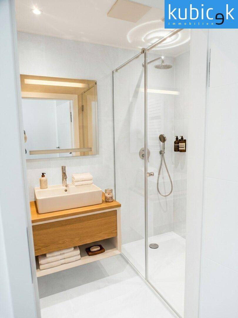 Modernes Badezimmer mit begehbarer Dusche, Regenbrause und elegantem Holzwaschtisch.