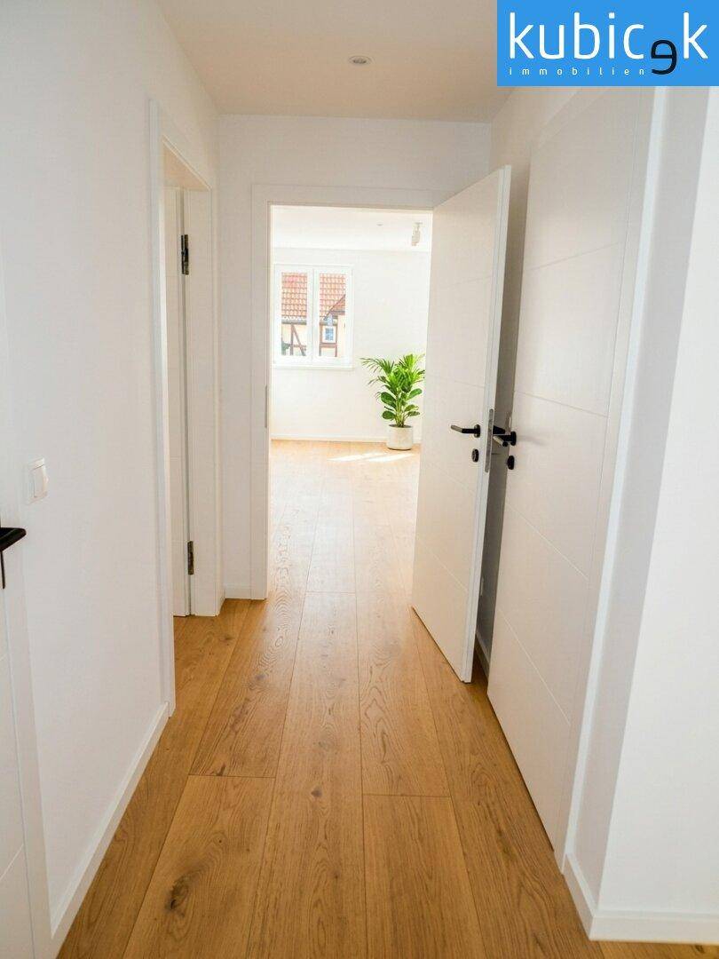 Heller Flur mit Holzboden und weißen Türen, der zu weiteren Räumen führt.