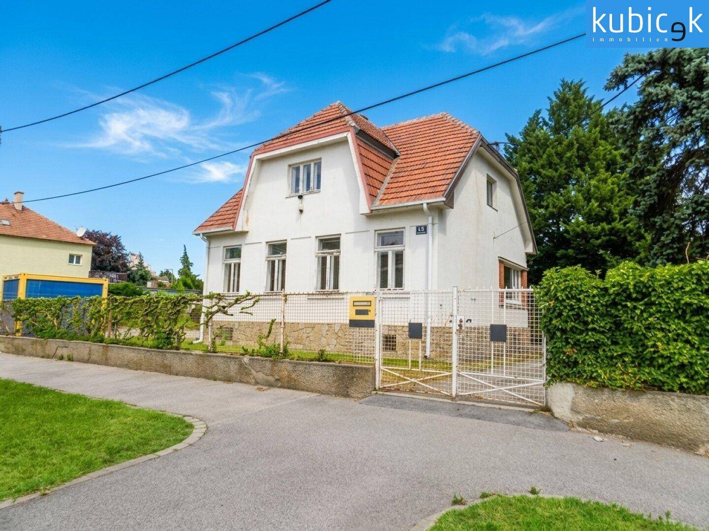 Vorderansicht des Hauses von der Straße mit Eingangstor und gepflegtem Vorgarten.