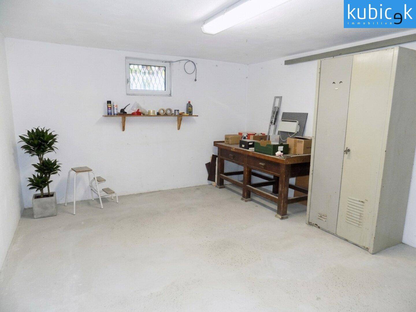 Kellerraum als Werkstatt genutzt mit Werkbank, Schrank und kleinem Fenster.