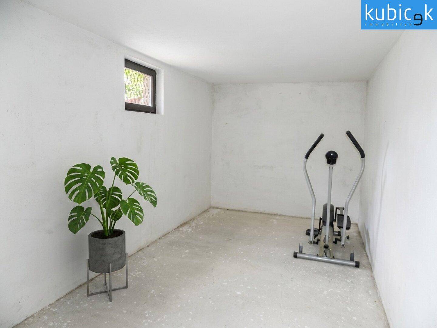 Kellerraum als Fitnessbereich mit Trainingsgerät, Betonboden und kleinem Fenster.