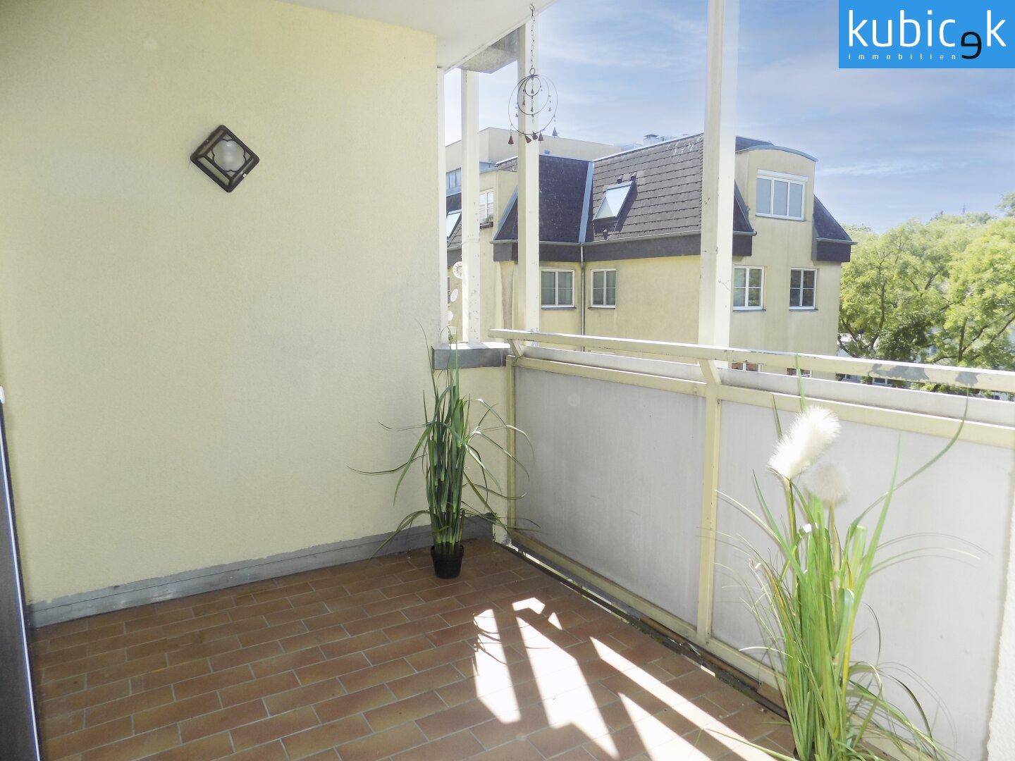 Heller Balkon mit Terrakotta-Fliesenboden und Pflanzen, ideal für entspannte Stunden im Freien.