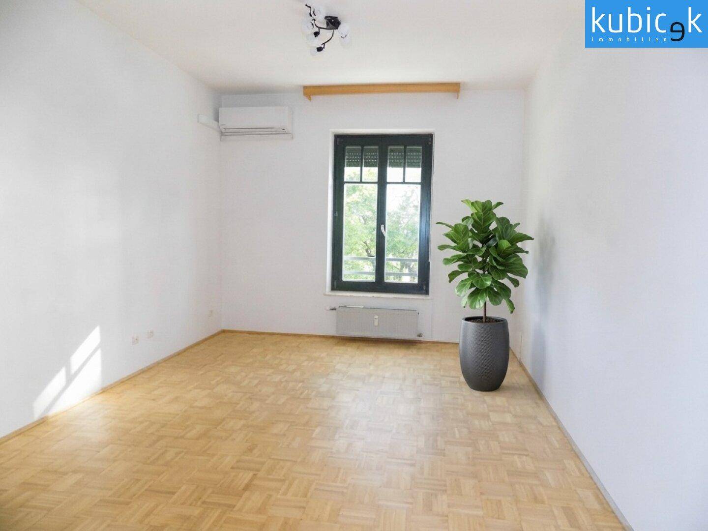 Heller Raum mit Parkettboden, Klimaanlage und einem großen Fenster.