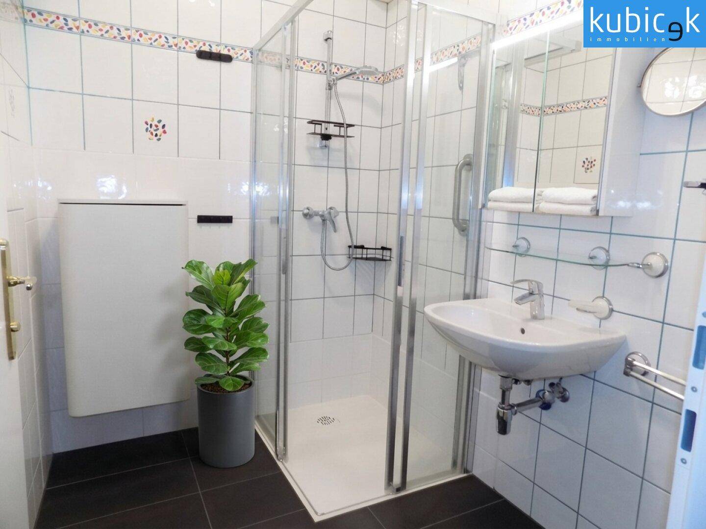 Modernes Badezimmer mit Duschkabine, Waschbecken und weißen Fliesen.
