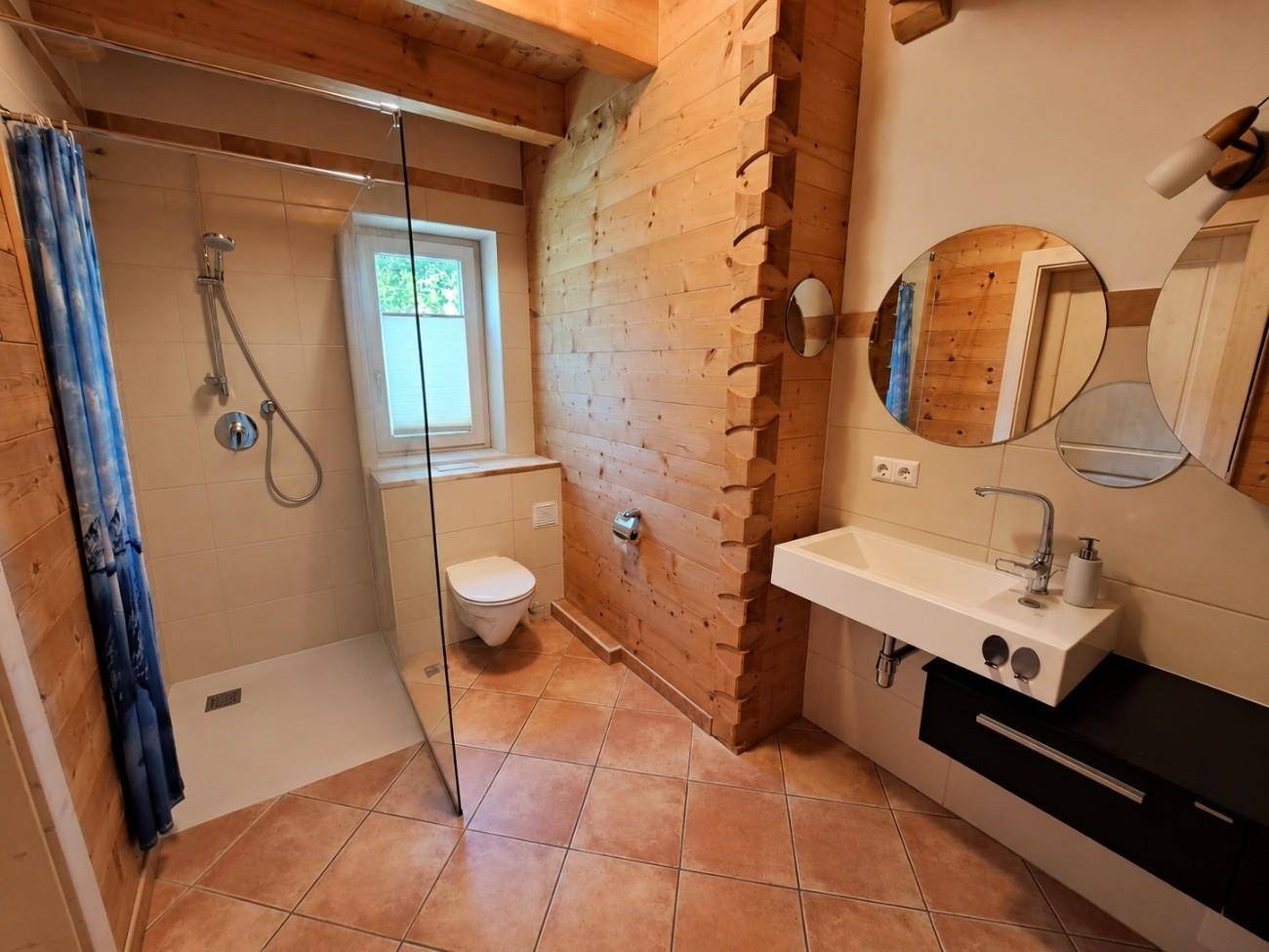 Modernes Badezimmer mit begehbarer Dusche, Holzvertäfelung und Fenster.