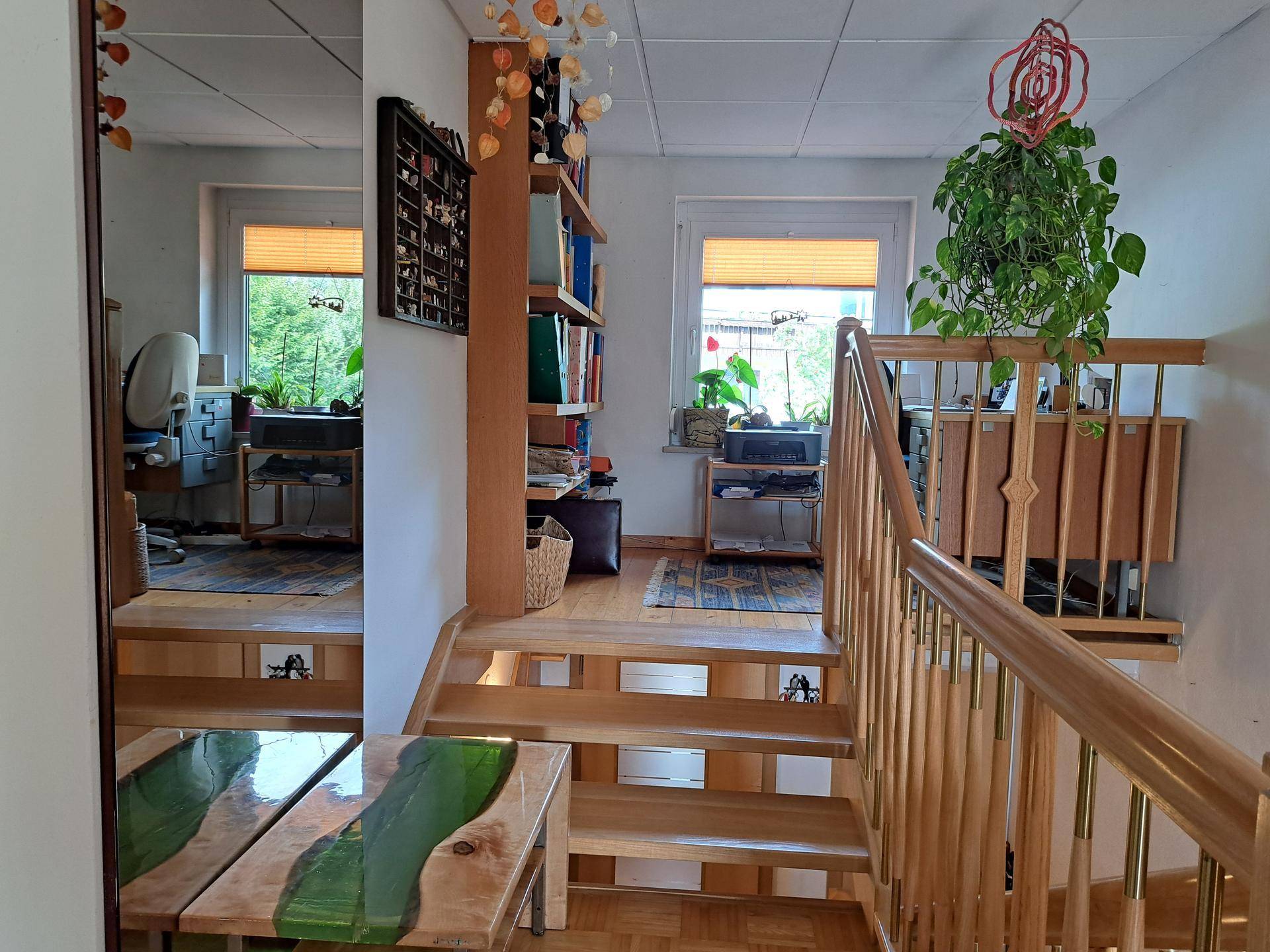 Obere Etage mit Holztreppe, die zu einem hellen Arbeitsbereich und weiteren Zimmern führt.