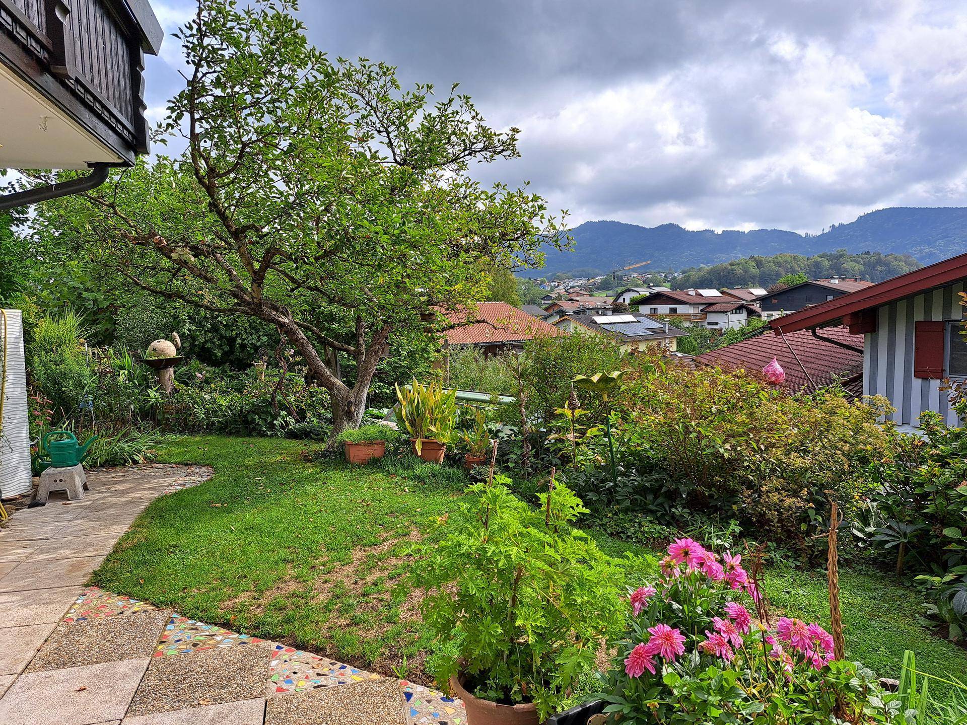 Gepflegter Gartenbereich mit Rasenfläche, Blumenbeeten und Blick auf die umliegende Landschaft.