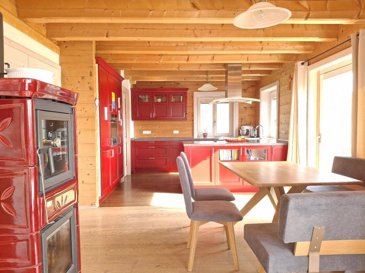 Offene Küche im Landhausstil mit roten Schränken, Holzbalkendecke und Essbereich.