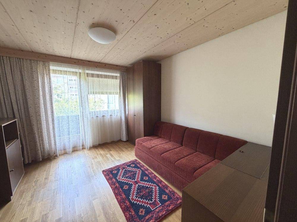 Schlaf- oder Gästezimmer mit Schlafsofa, Holzdecke und großem Fenster.