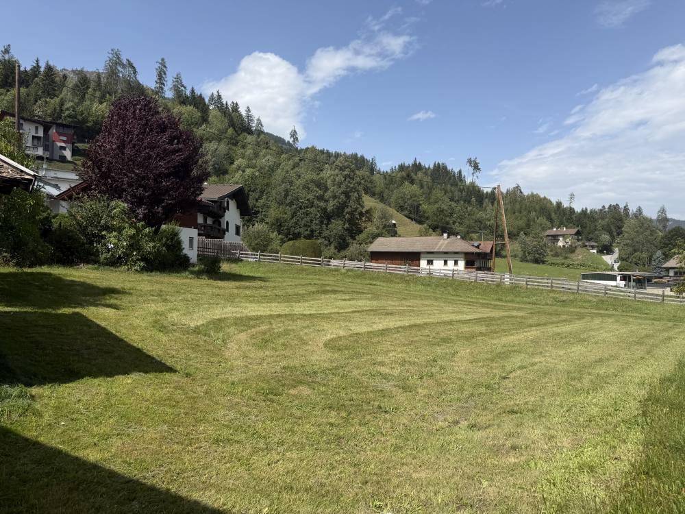 Sonniges Grundstück mit gemähtem Rasen und idyllischem Bergblick.