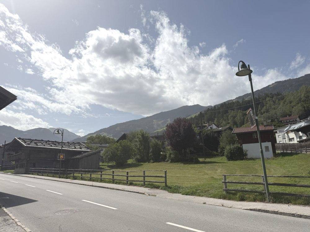Blick von der Straße auf das Grundstück mit umliegender Berglandschaft.