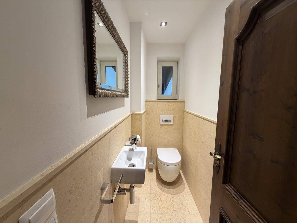 Modernes Gäste-WC mit wandhängendem WC, kleinem Waschbecken und Fenster.
